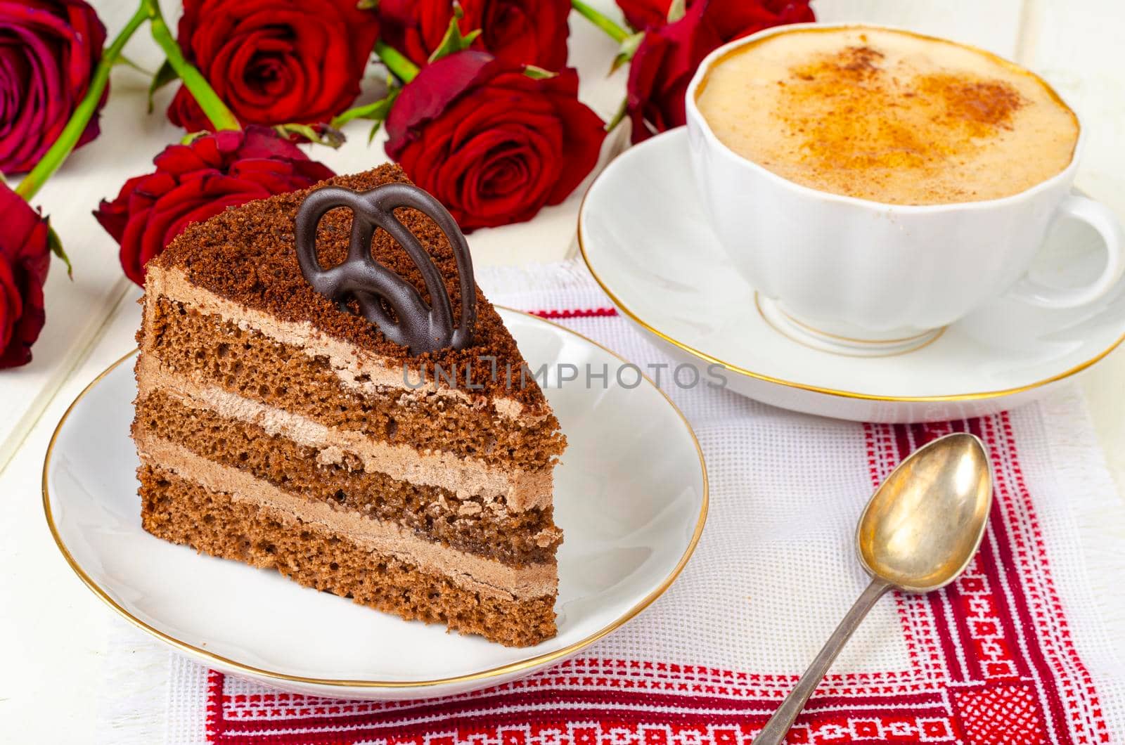 Piece of chocolate cake, cappuccino, flowers on table. Studio Photo