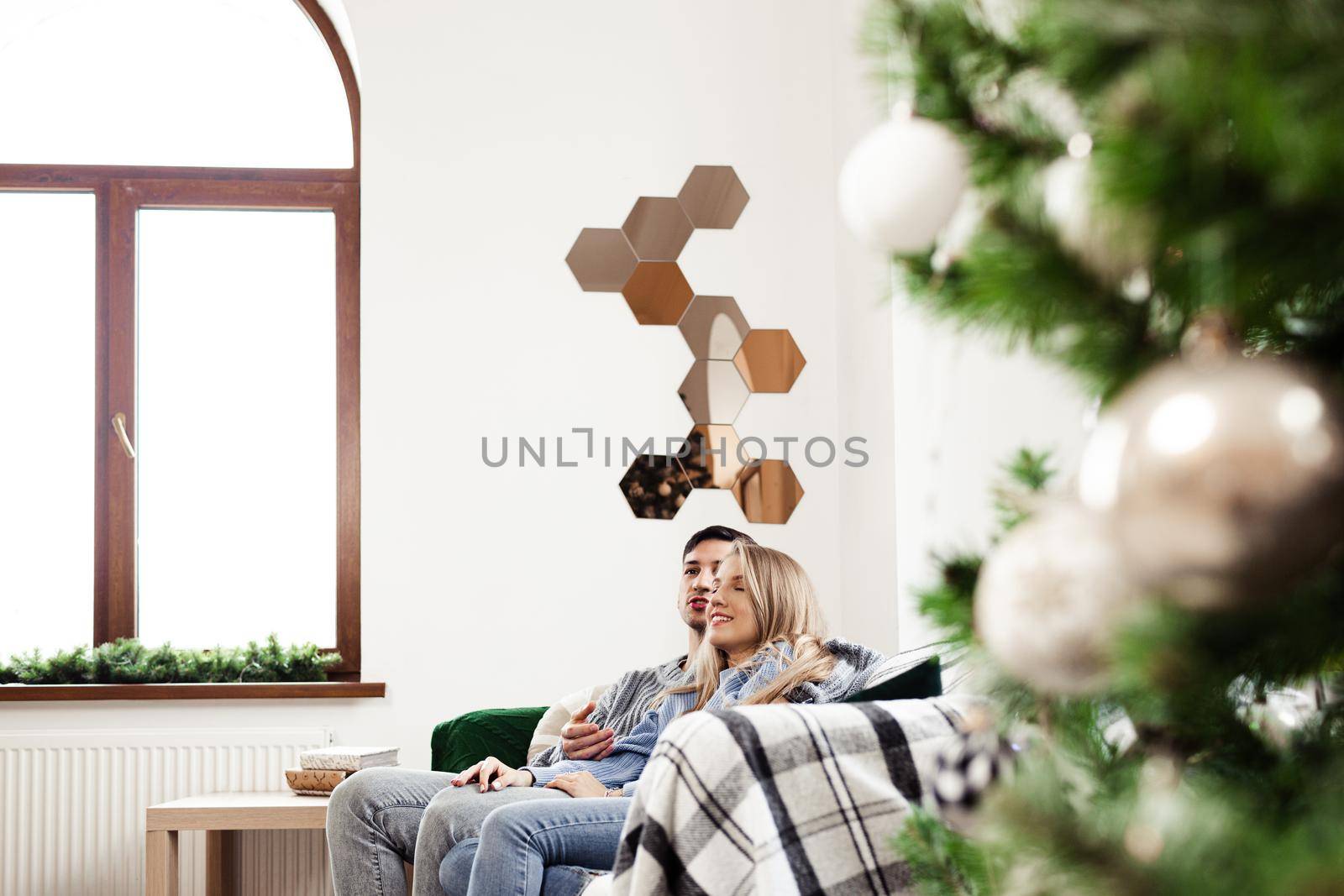 Sweet couple embracing on sofa at home during christmas holidays