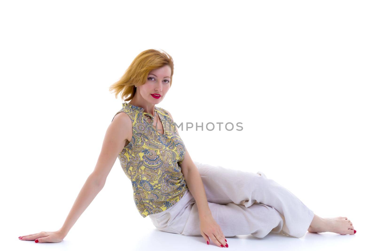 Beautiful young woman sitting on the floor of a studio. The concept of style and fashion. Isolated on white background.