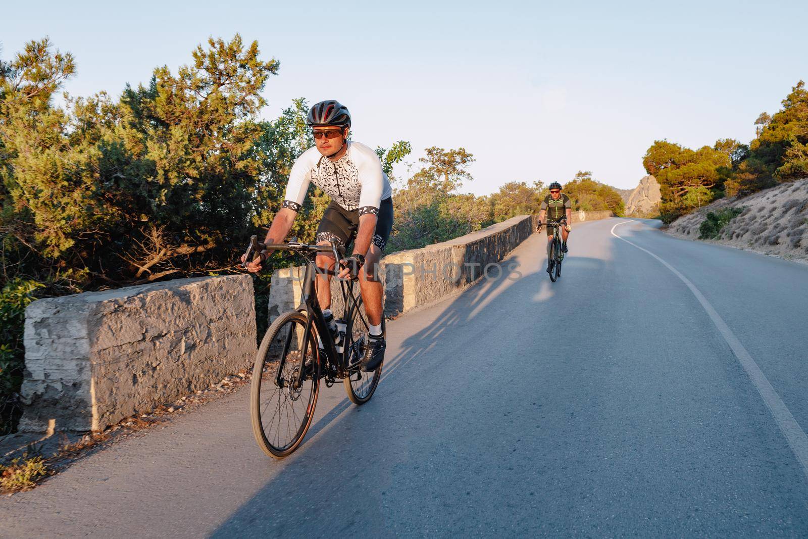 Two professional male cyclists riding their racing bicycles in the morning together on coastal road