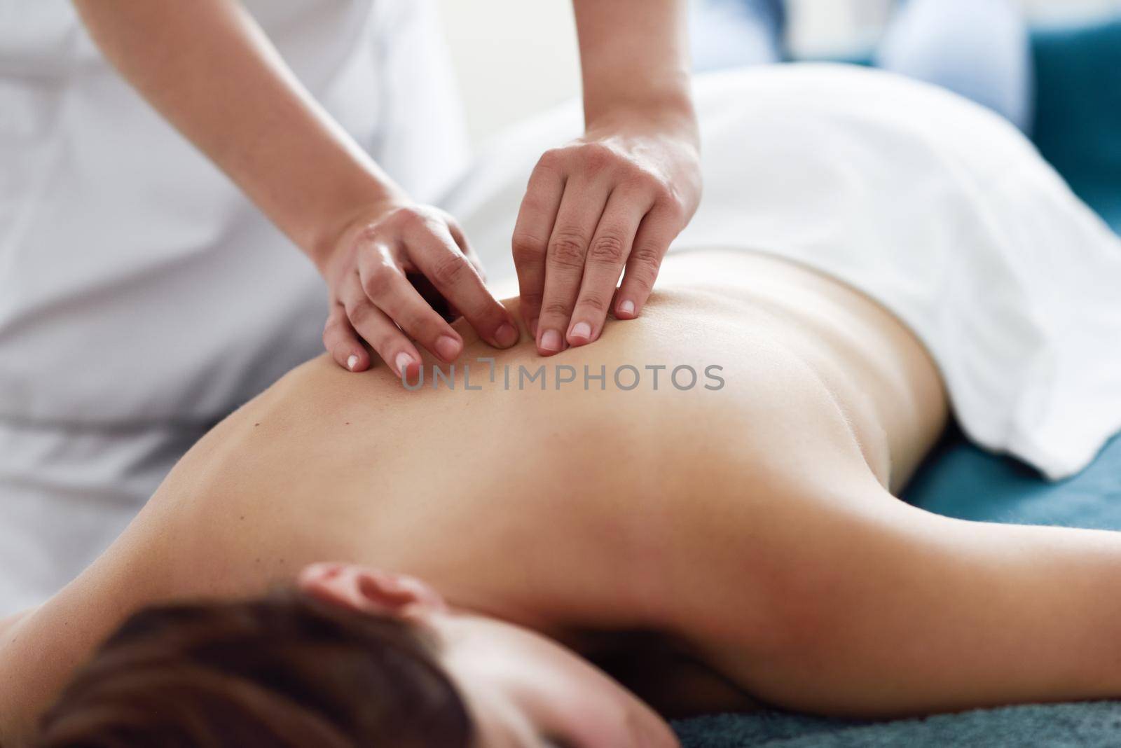 Young woman receiving a back massage by professional therapist. Female patient is receiving treatment in a spa center.