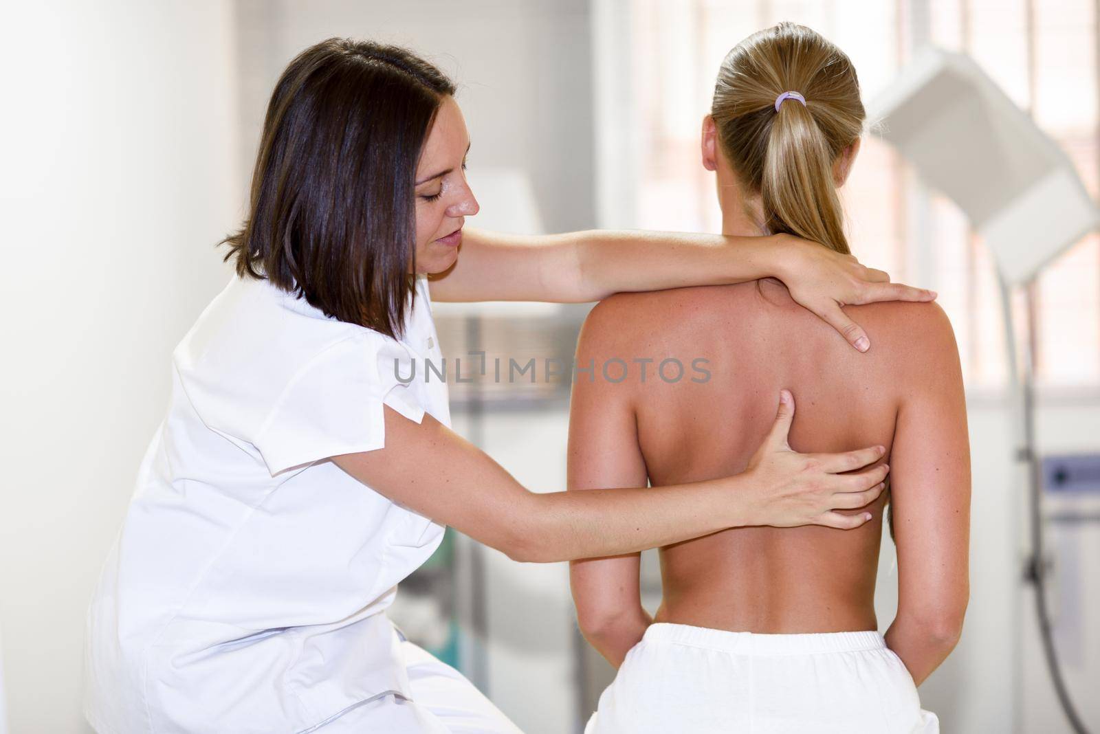 female physiotherapist inspecting her patient. Medical check at the shoulder in a physiotherapy center.