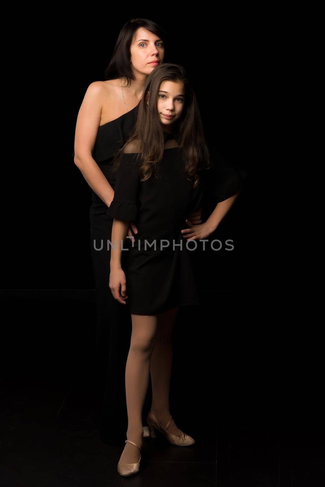 Happy family mom and daughter in the studio on a black background. The concept of love, childhood.