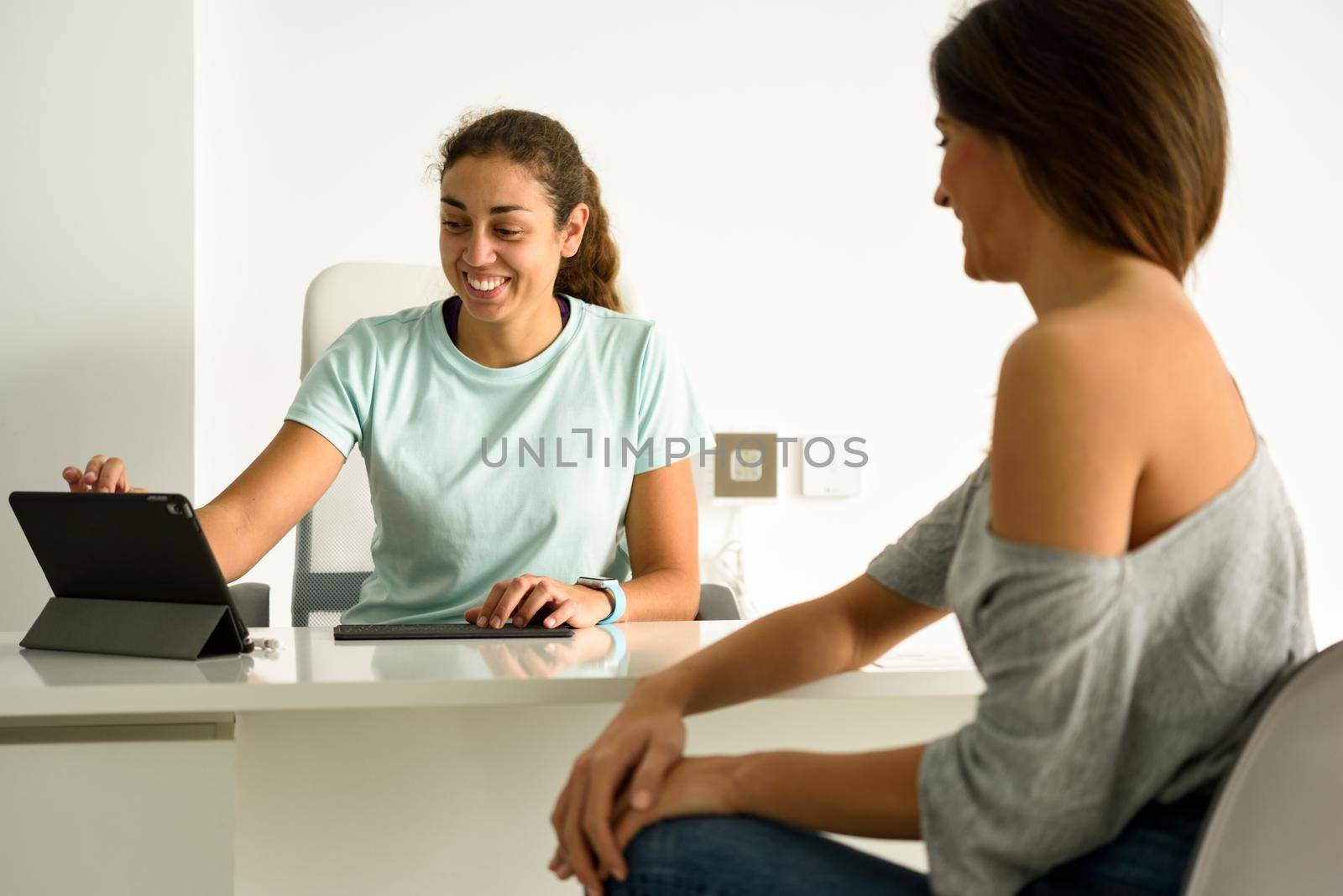 Female physiotherapist explaining diagnosis to her patient. Brunette woman having consultation with girl in medical office.