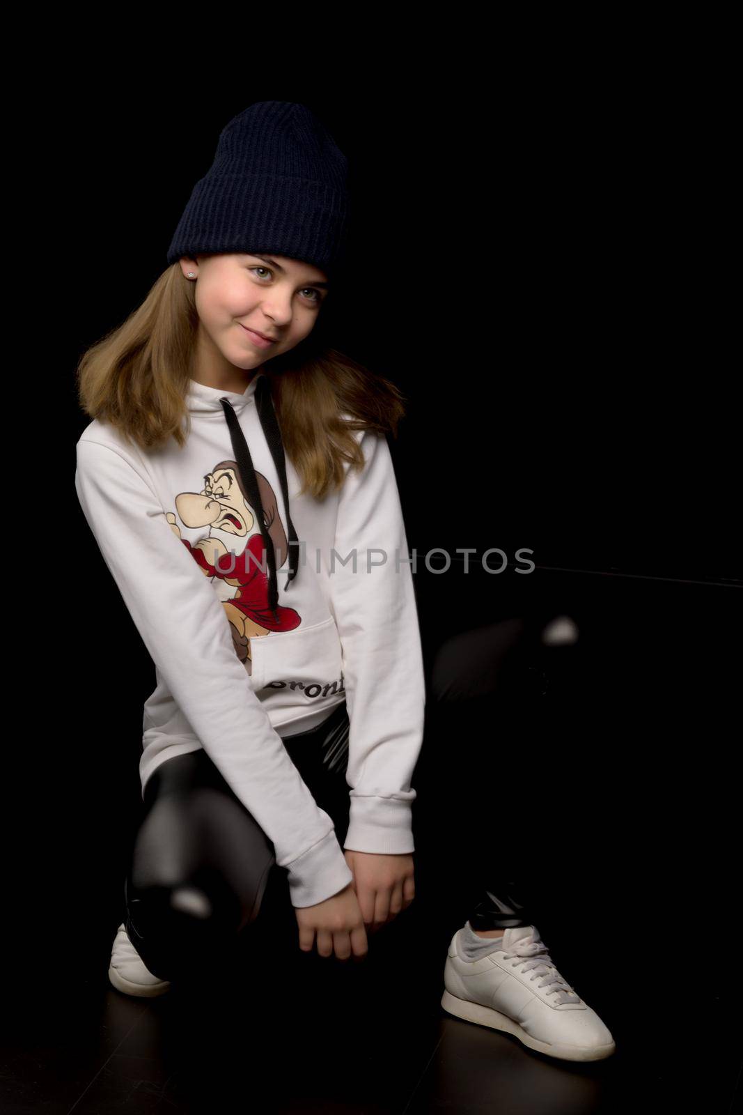 The concept of youth sports and clothes.Beautiful little teenager girl in a sports youth suit. On a black background.