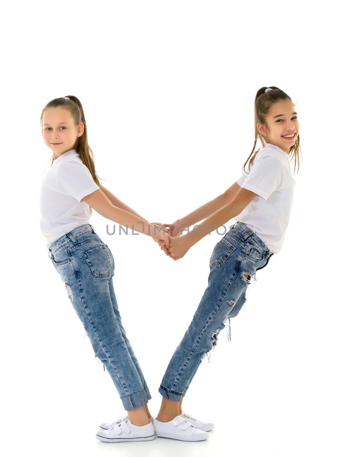 Two cute little girls are holding hands. Studio photography.Isolated on white background.