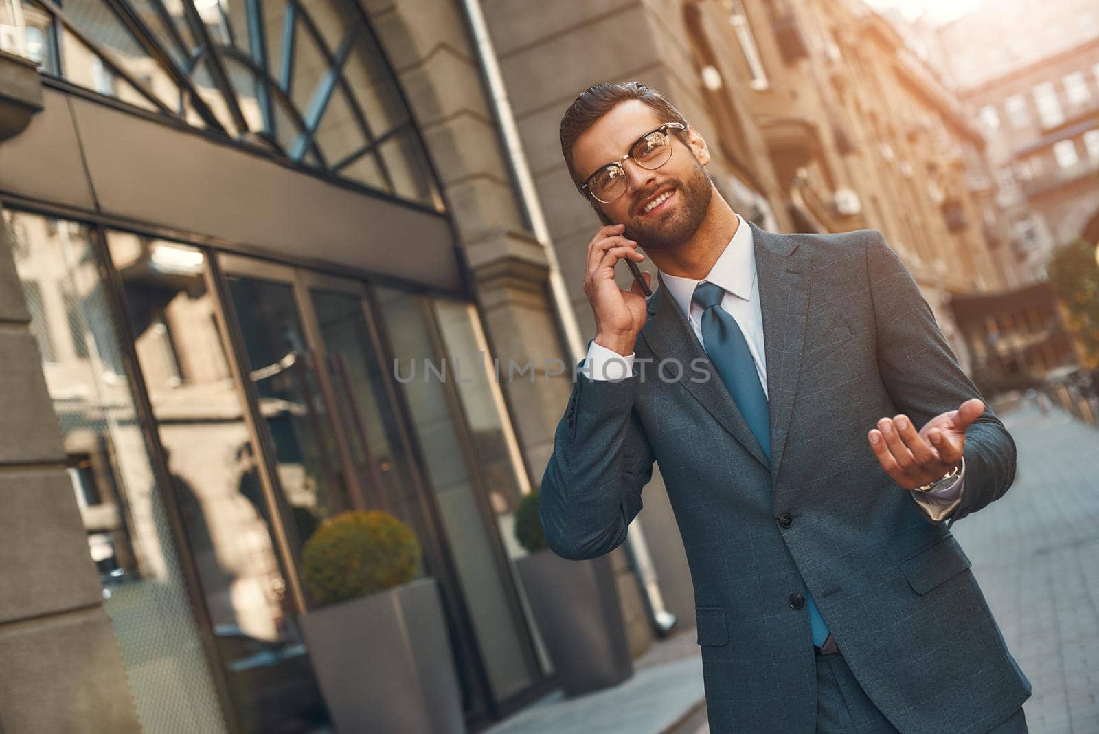 Happy to hear you Portrait of smiling bearded businessman in full suit talking by phone with client while walking outdoors by friendsstock