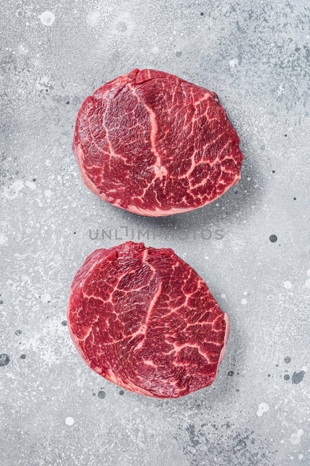 Raw fillet Mignon beef steaks on a butcher board. Gray background. Top view.