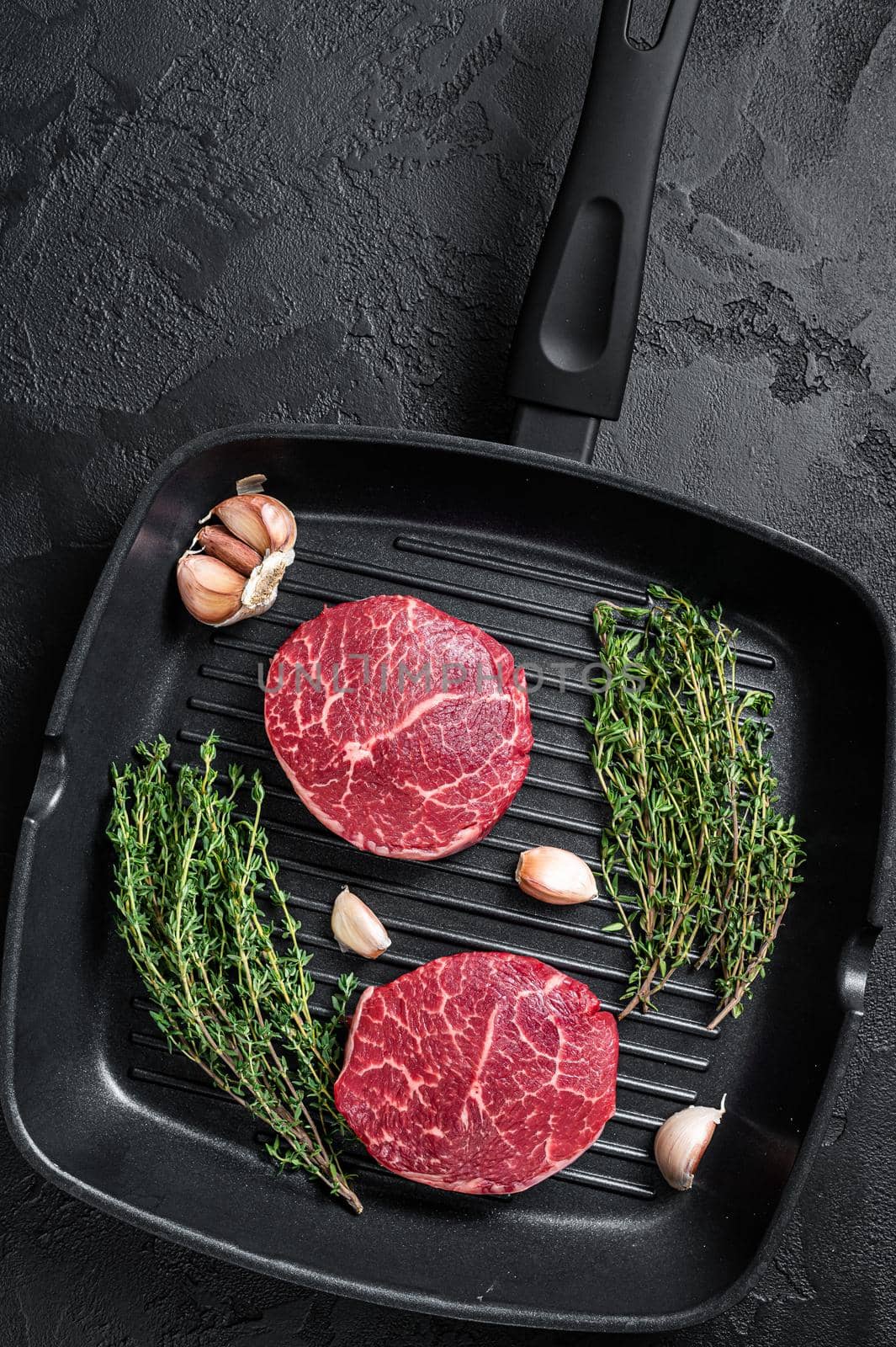 Tenderloin Raw Fillet Mignon beef steaks on a pan. Black background. Top view.