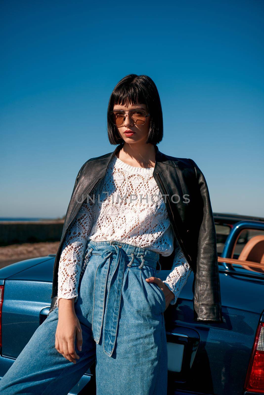 Close-up of young stylish woman with a haircut standing near roofless car by friendsstock