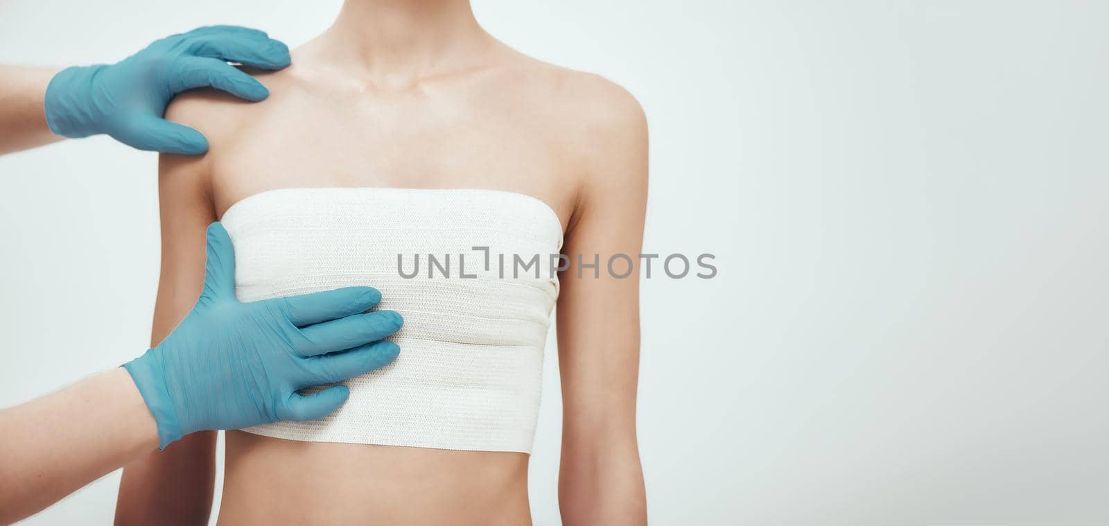 Increase your breast size. Cropped photo of woman waiting for plastic surgery while surgeons in blue medical gloves measuring her breast by friendsstock