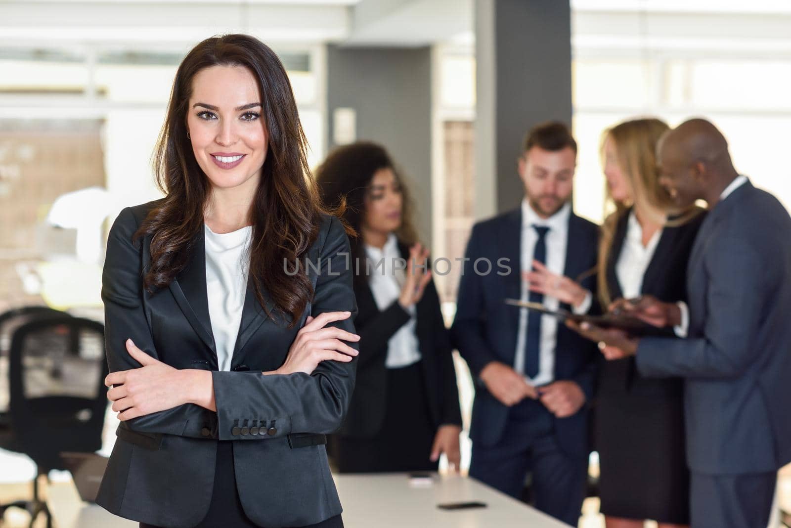 Businesswoman leader in modern office with businesspeople working at background by javiindy