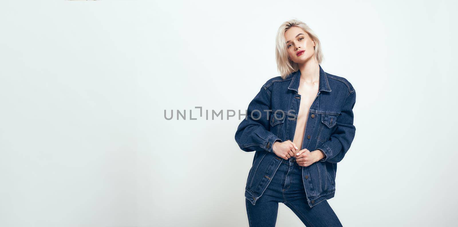 Confident in my style. Cute young woman in jeans wear looking at camera while standing against grey background in studio. Denim. Fashion concept. Beauty