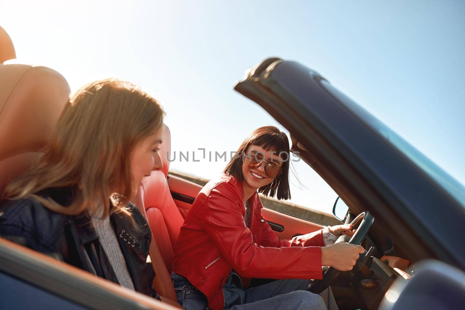 Two happy friends in the cabriolet driving everywhere and looking for freedom and fun