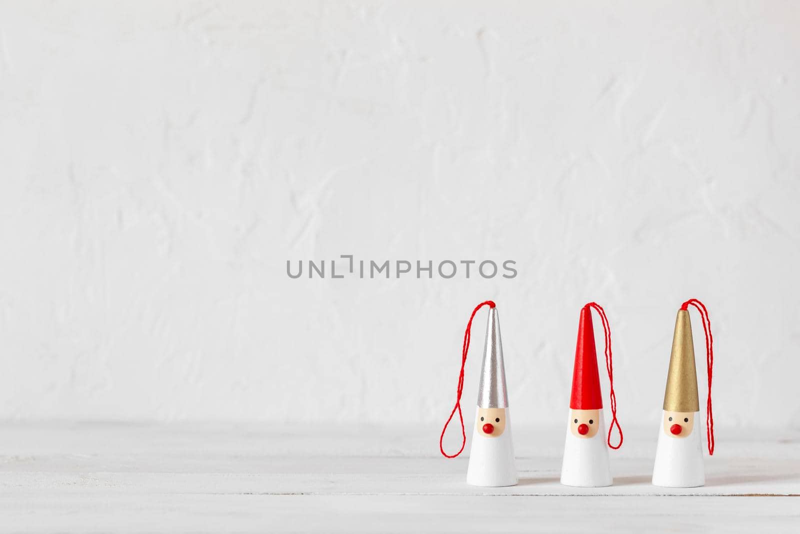 three Santa Clauses figurines on a white wooden background, side view, copy space