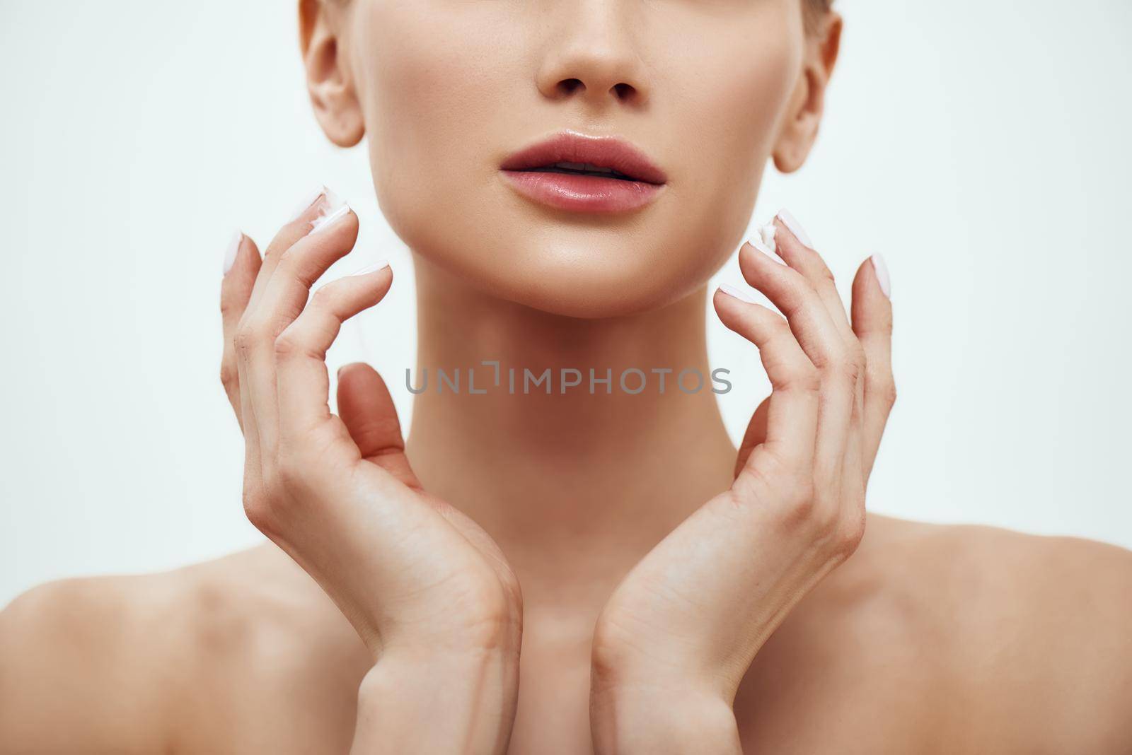 Pure beauty. Cropped photo of young blonde woman touching her soft and fresh skin while standing against grey background. Skin care by friendsstock