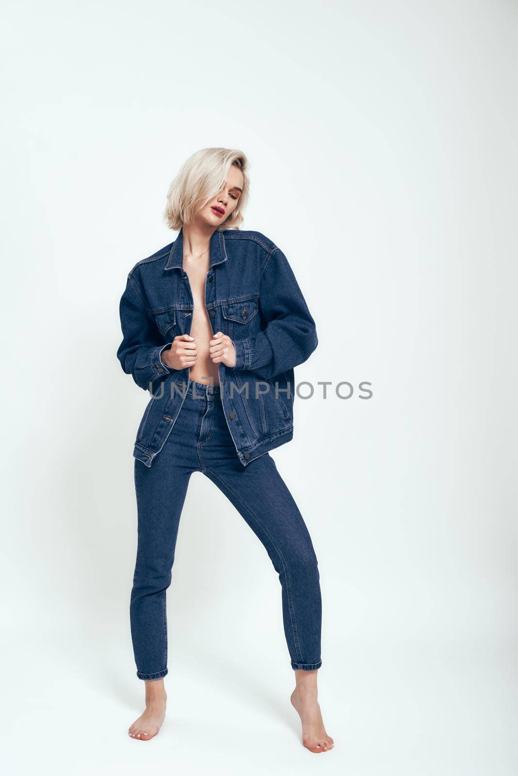 Confident and sexy. Full length of attractive young woman in jeans wear looking aside while standing against grey background in studio. Denim. Fashion concept. Beauty