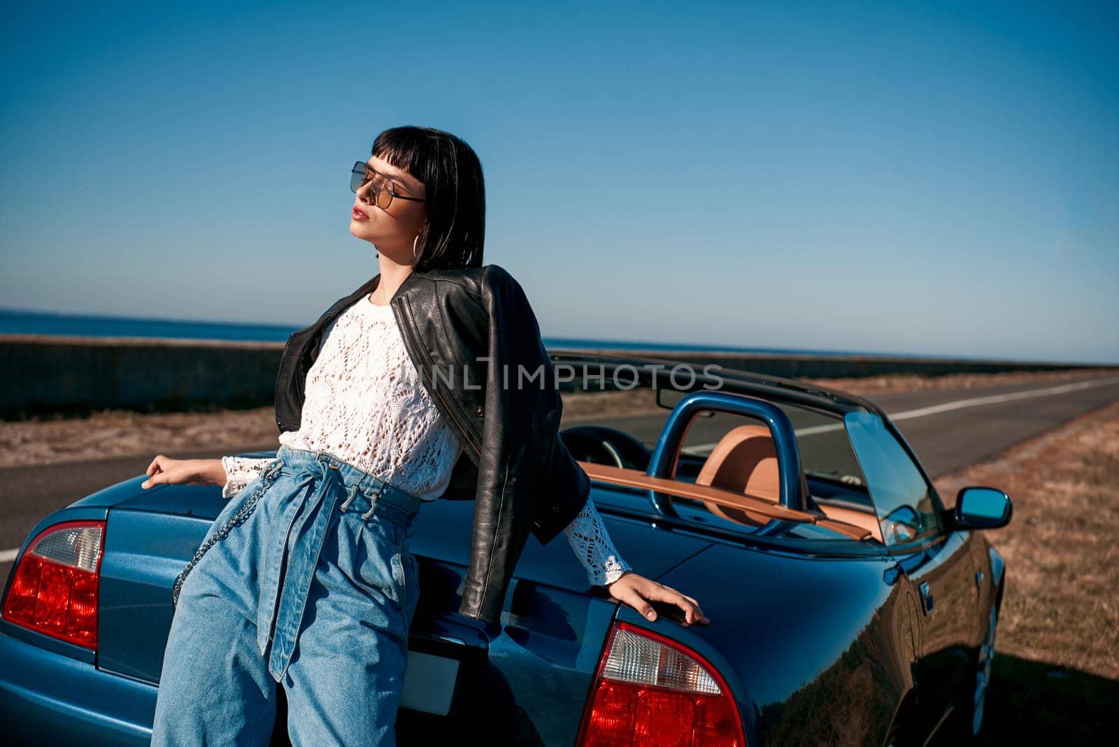 Close-up of young stylish woman with a haircut standing near roofless car by friendsstock