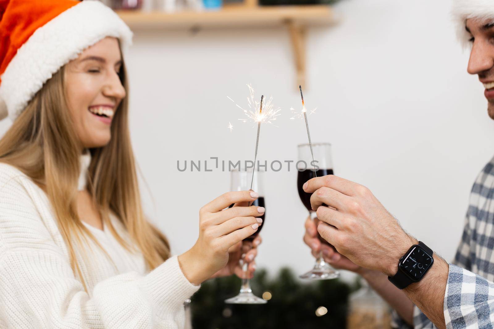 Young couple in Santa hats drinking wine and celebrating Christmas, close up