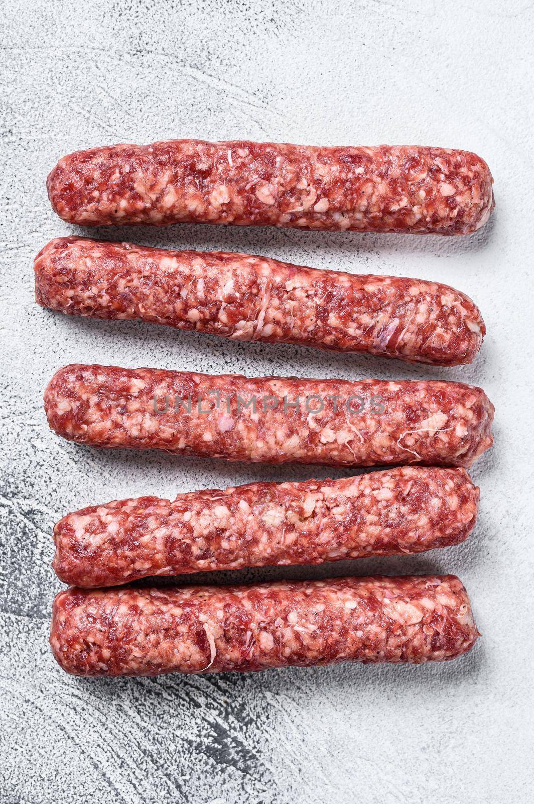 Fresh raw beef meat kebabs sausages. White background. Top view.
