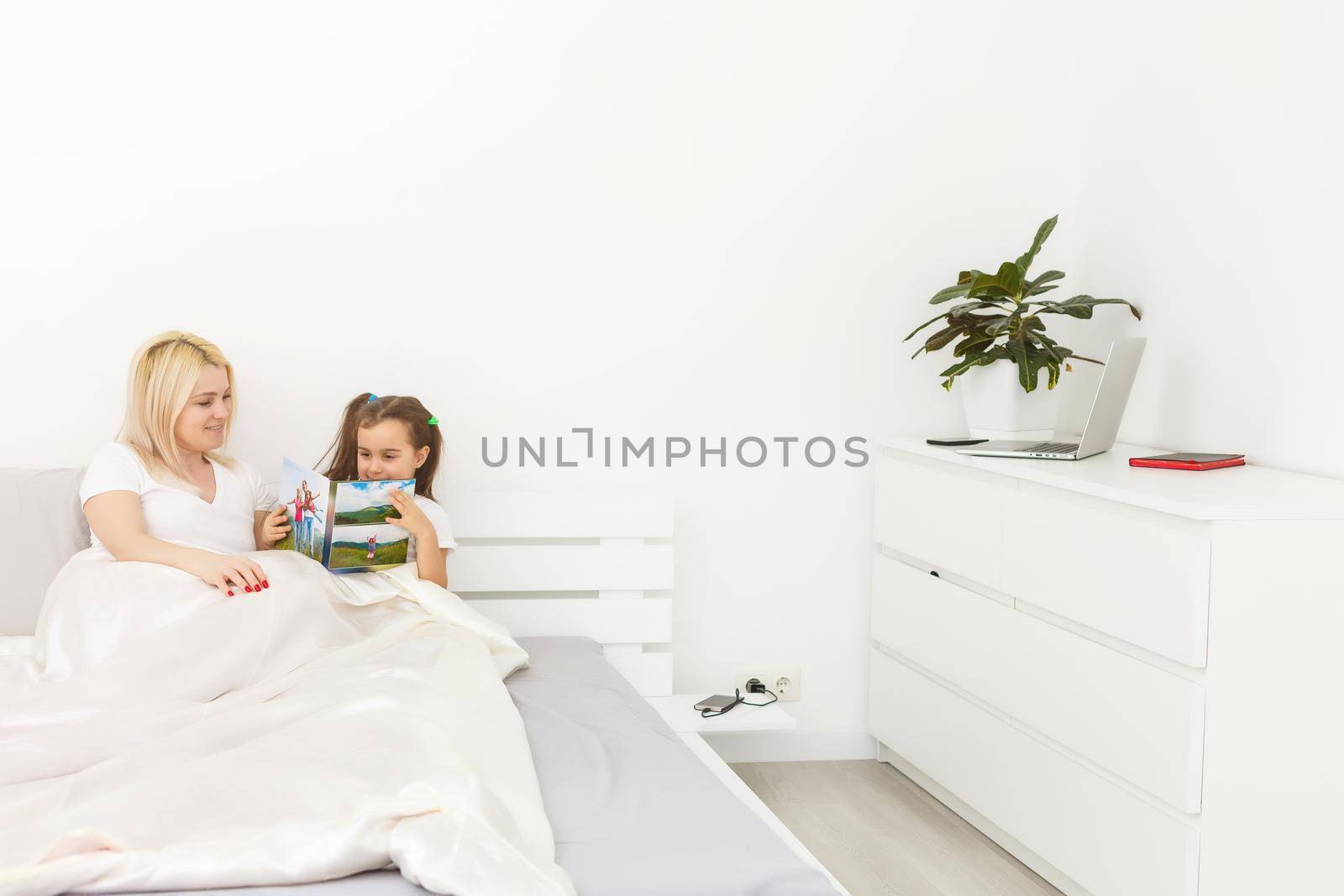 mother and daughter in bed watching a photo book