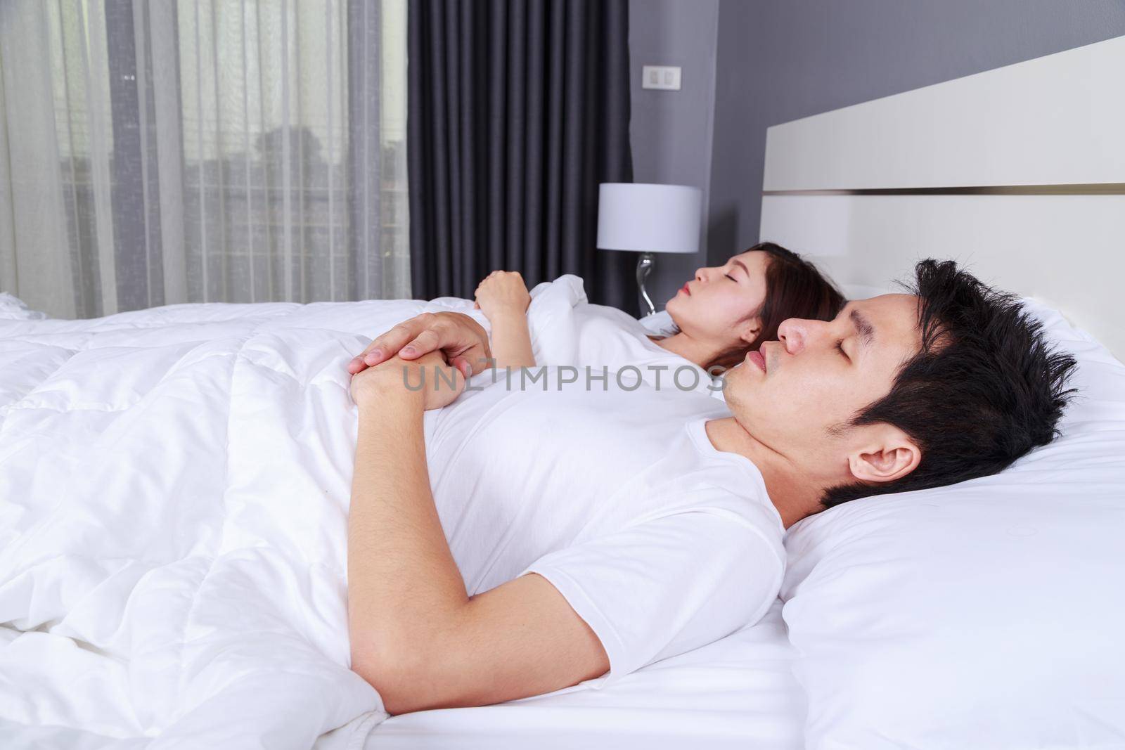 young couple sleeping on a comfortable bed in bedroom at home