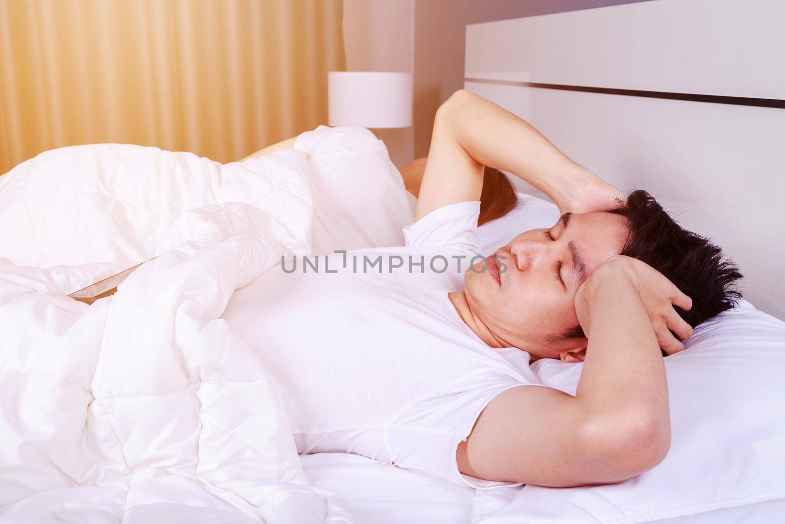 man having sleepless on bed and having migraine,stress, insomnia, hangover in the bedroom