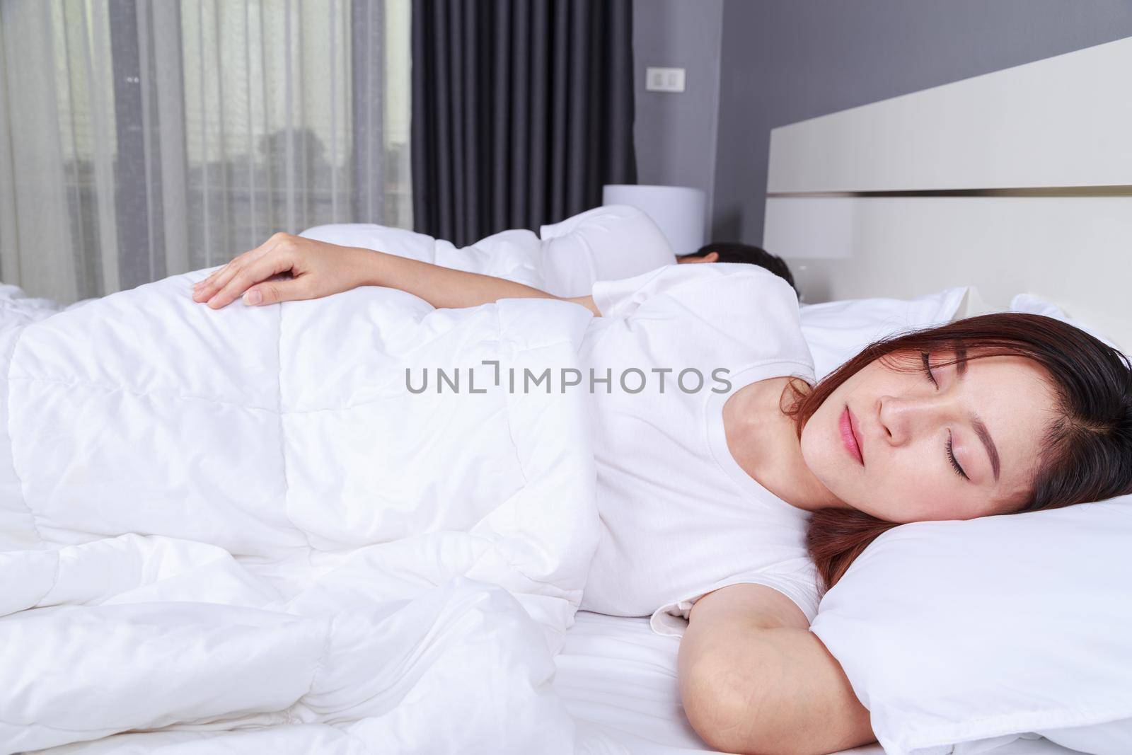 woman sleeping with her husband in a comfortable bed at home by geargodz