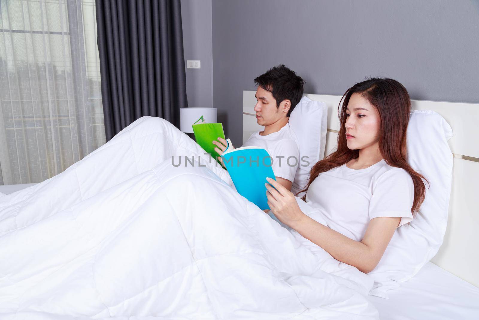 young couple reading a book on bed in the bedroom