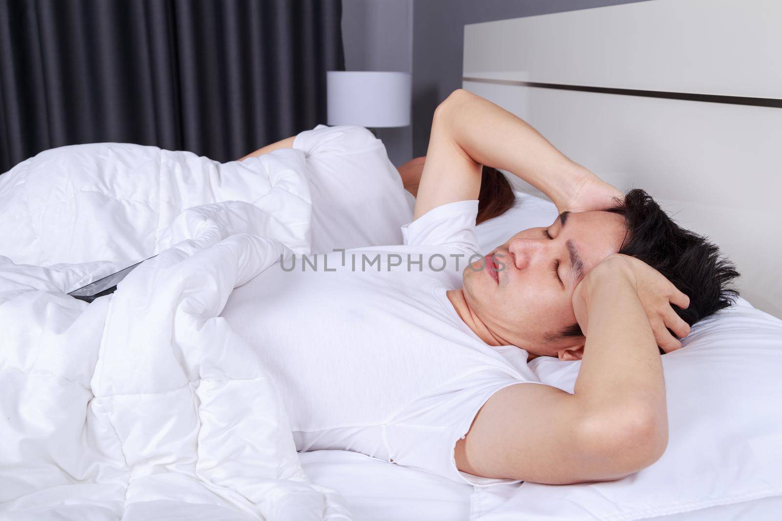 man having sleepless on bed and having migraine,stress, insomnia, hangover in the bedroom