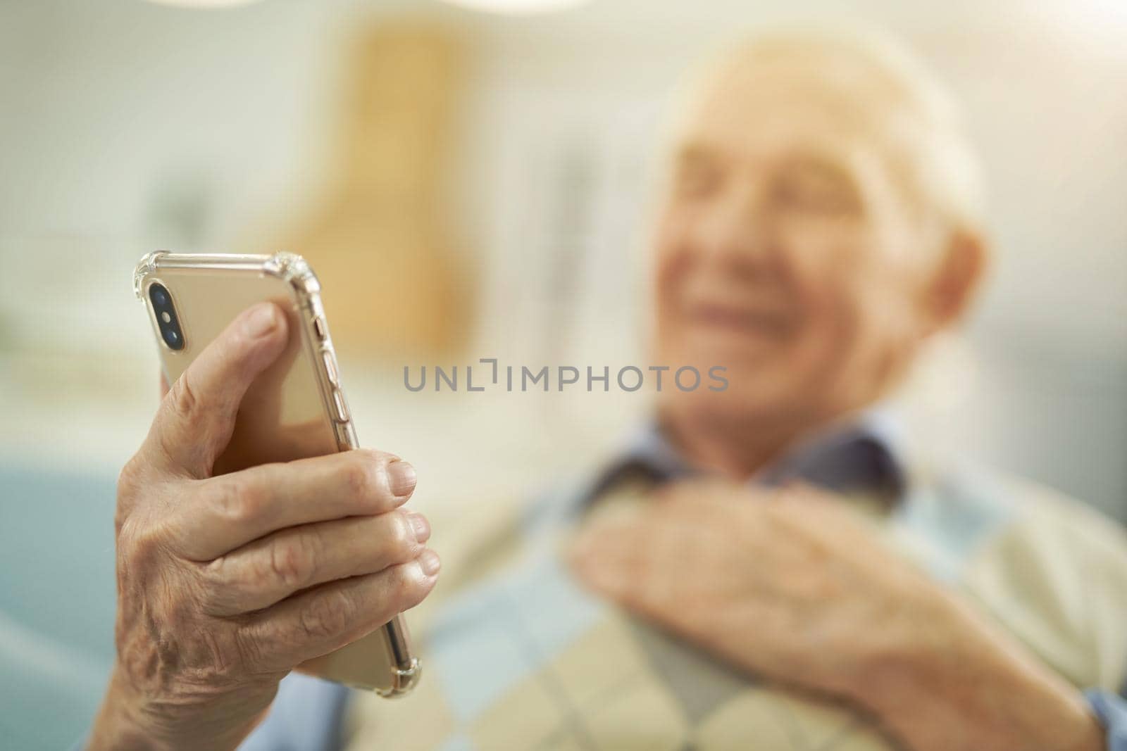 Happy male pensioner enjoying the conversation on the phone online at home