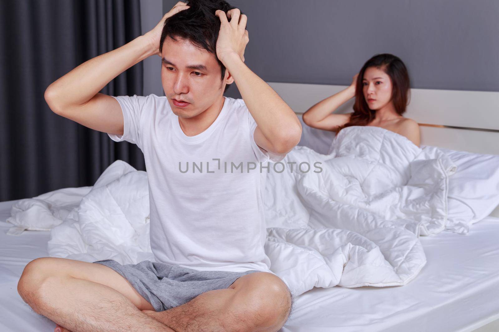upset man having problem sitting on the bed with his wife in the bedroom by geargodz
