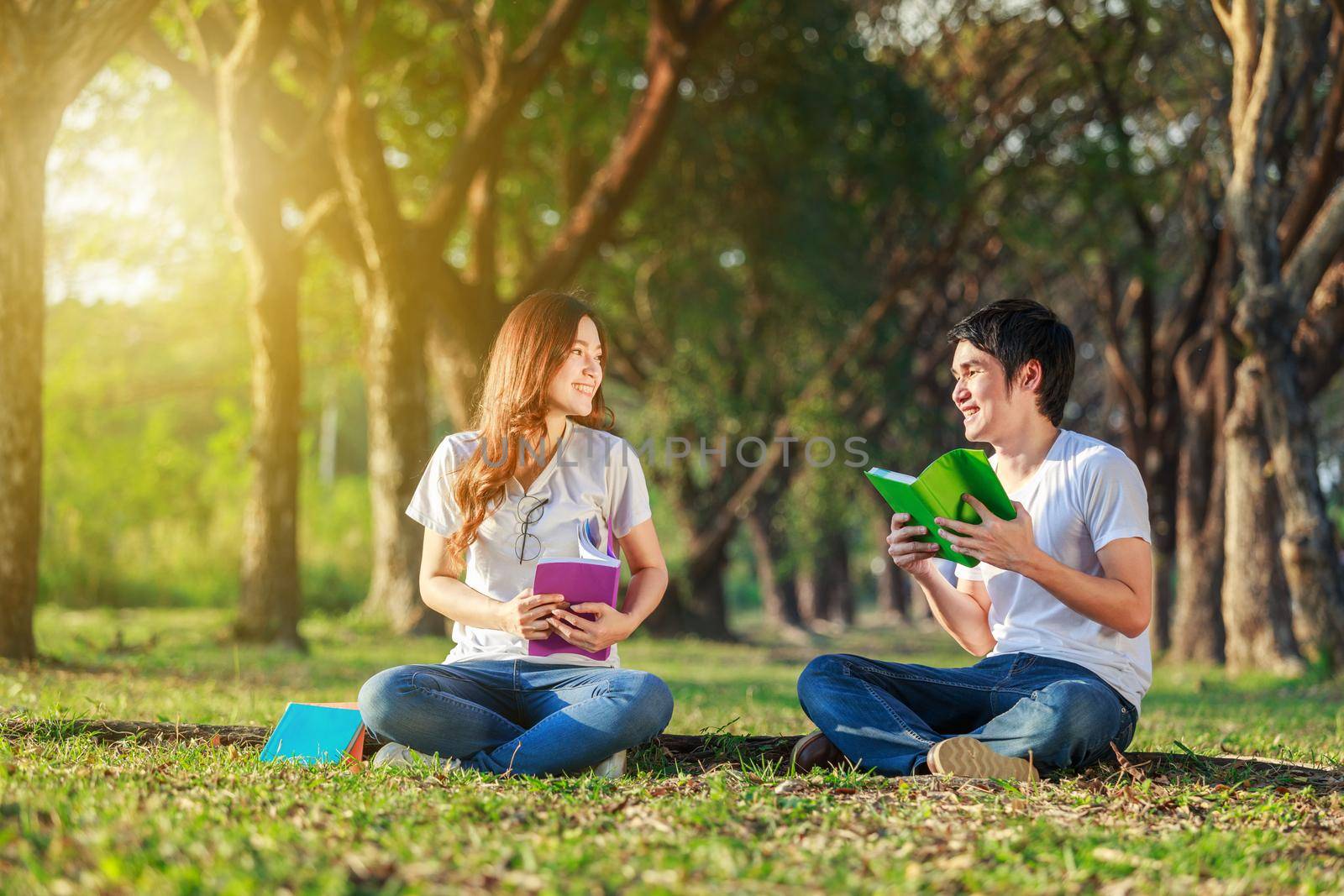 man and woman sitting and reading a book in the park