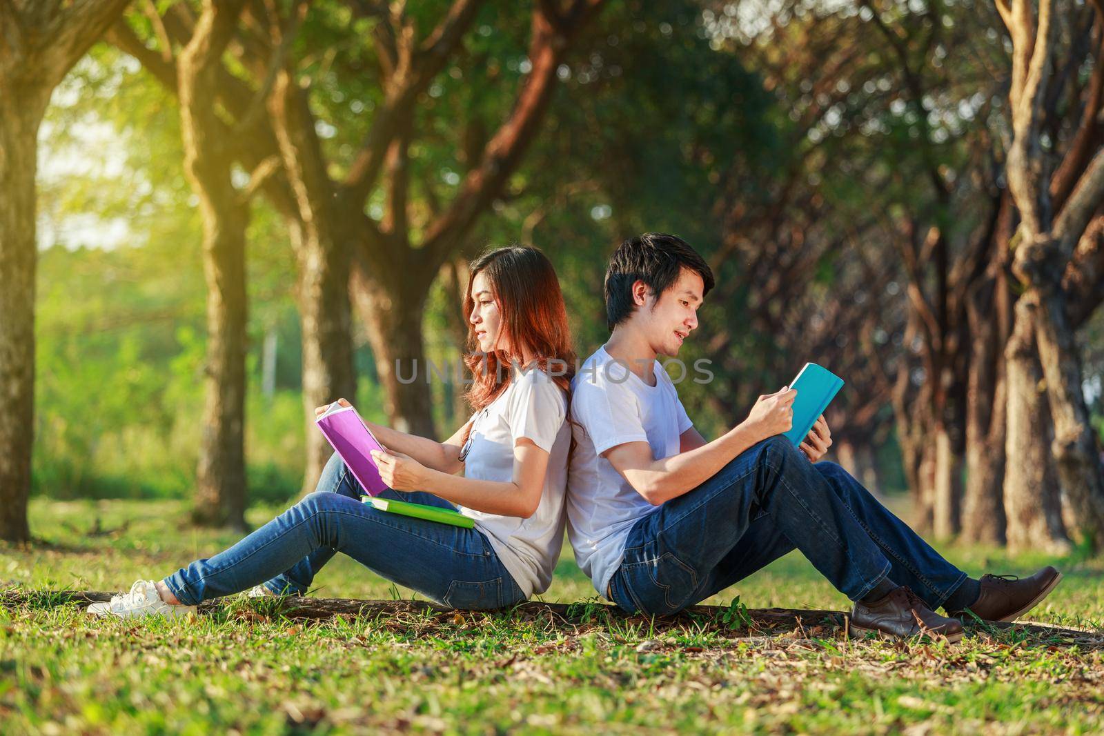 man and woman sitting and reading a book in park by geargodz
