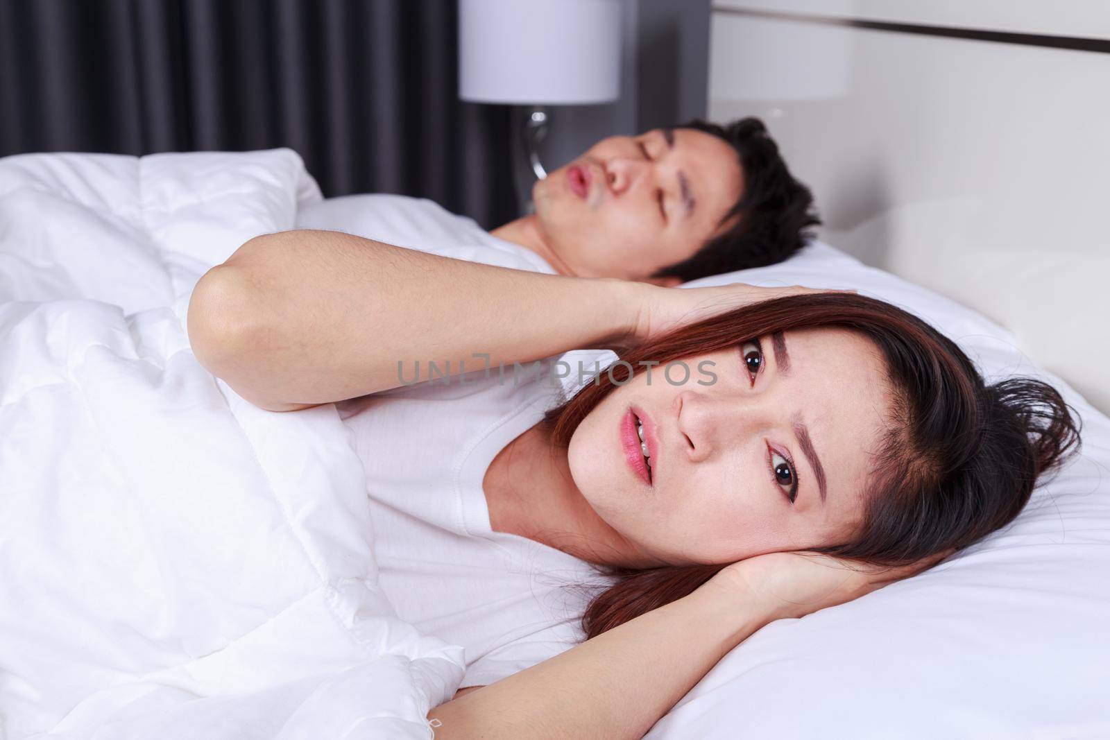 annoyed wife blocking her ears from noise of husband snoring in bedroom  by geargodz