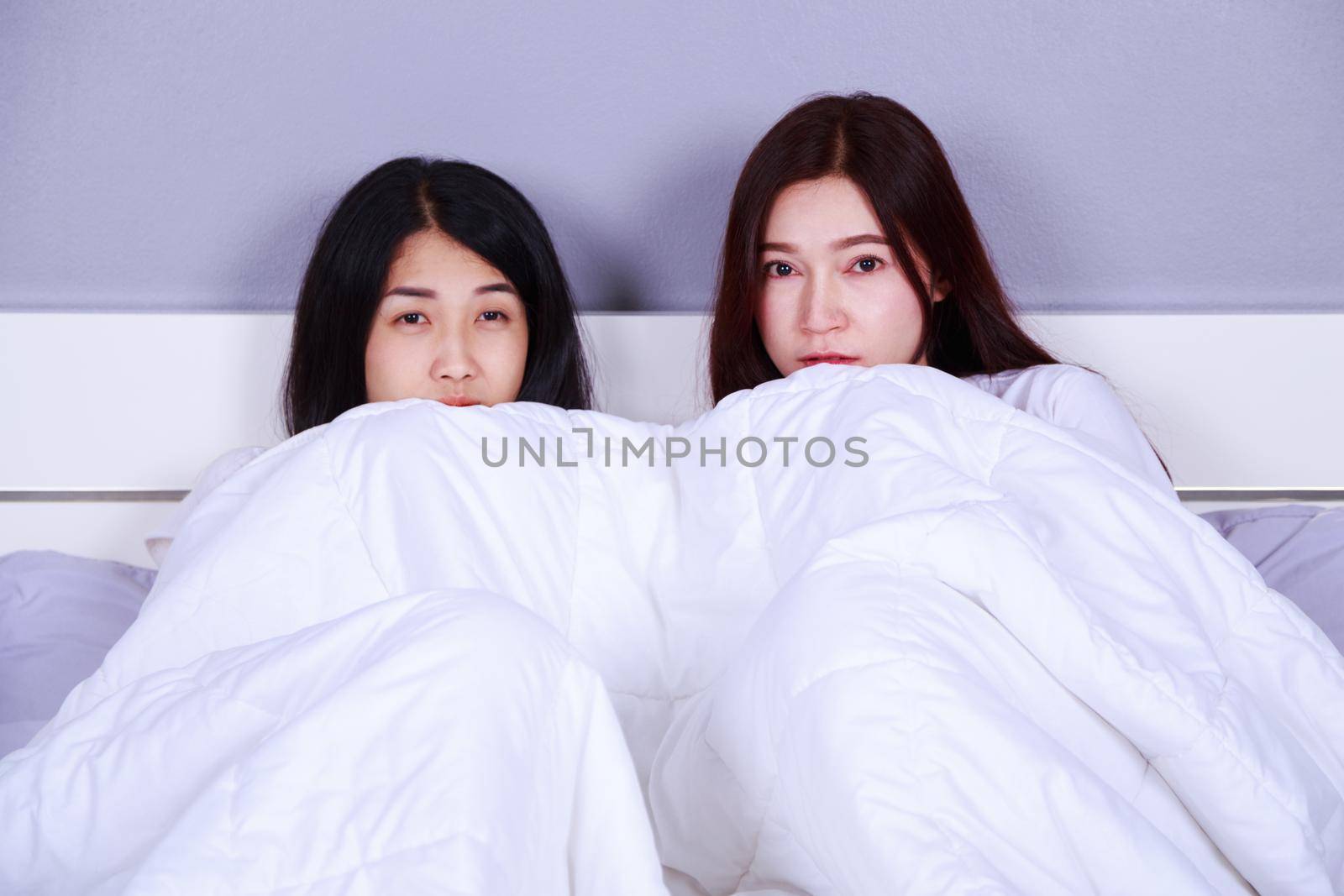two best friend woman on bed watching a tv with shocked expression on face