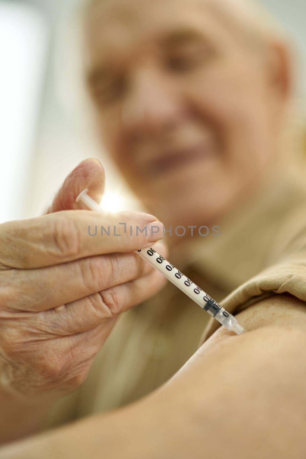 Selective focus of syringe in the arm being used by a mirthful senior citizen