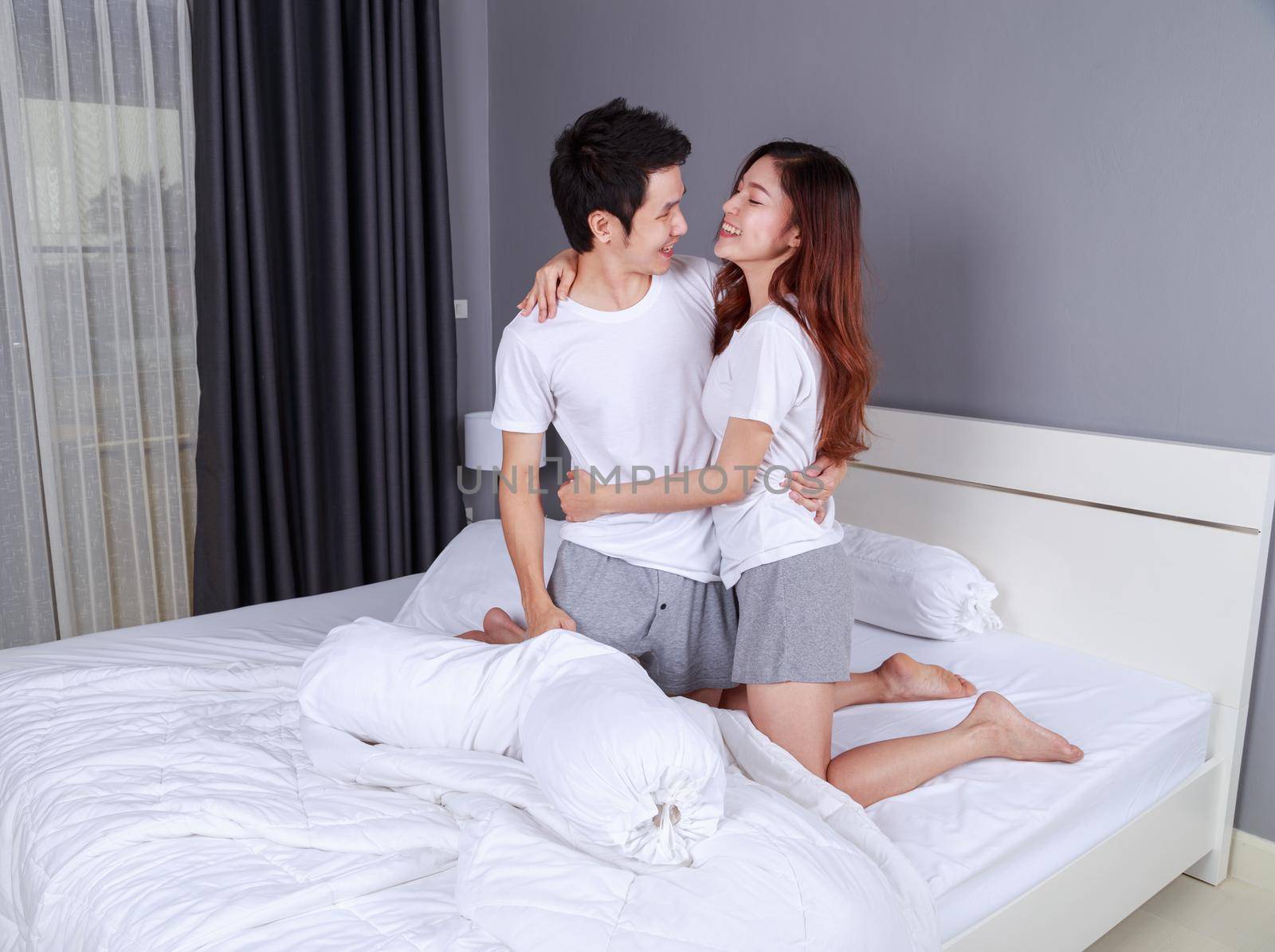 happy young attractive couple hugging on bed in the bedroom