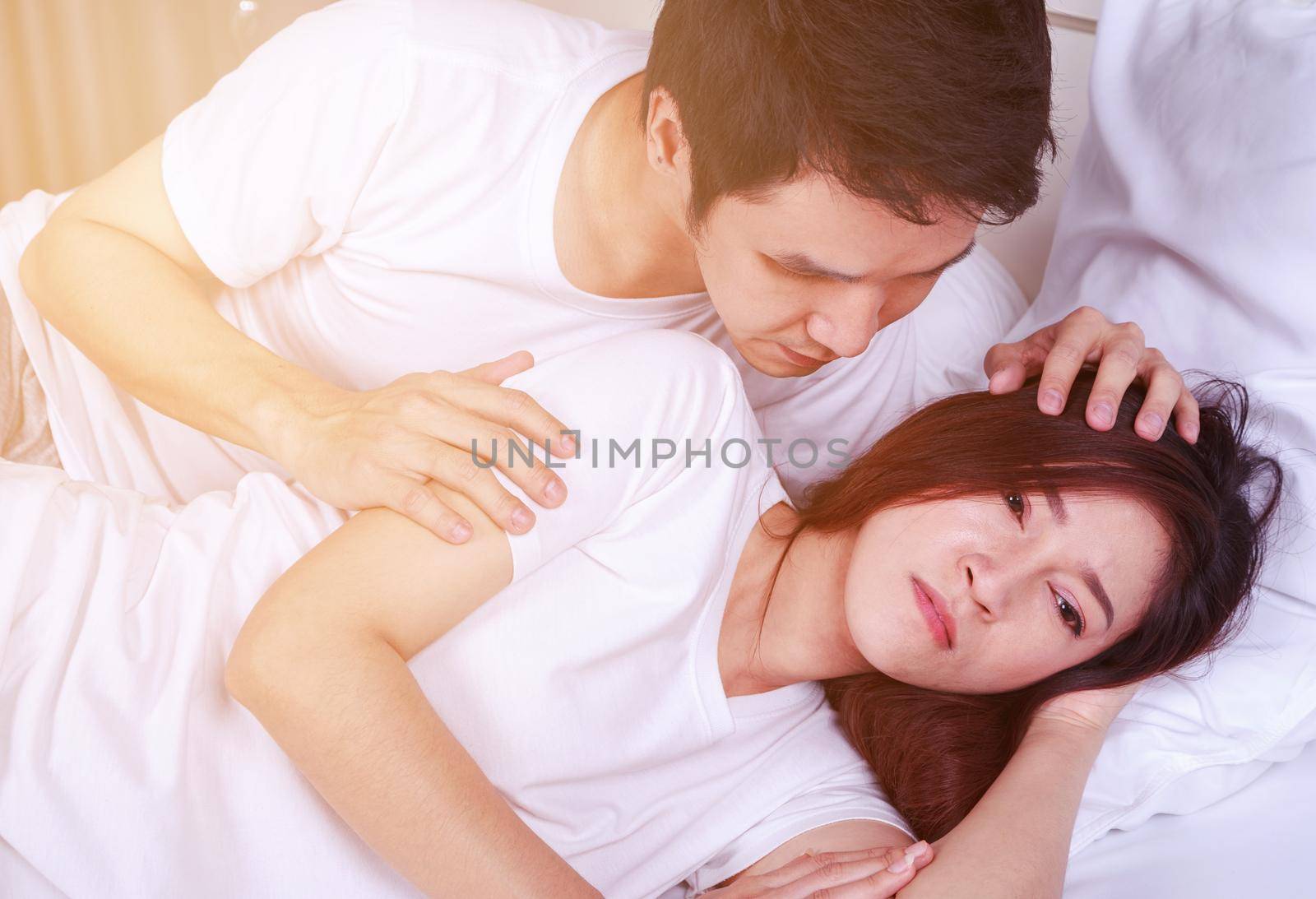 unhappy woman lying on bed with a concerned guy comforting her by geargodz