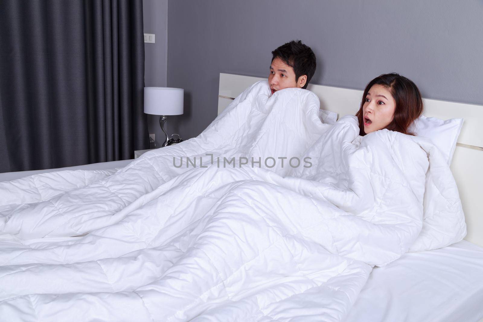 couple watching scared movie under the blanket on bed by geargodz