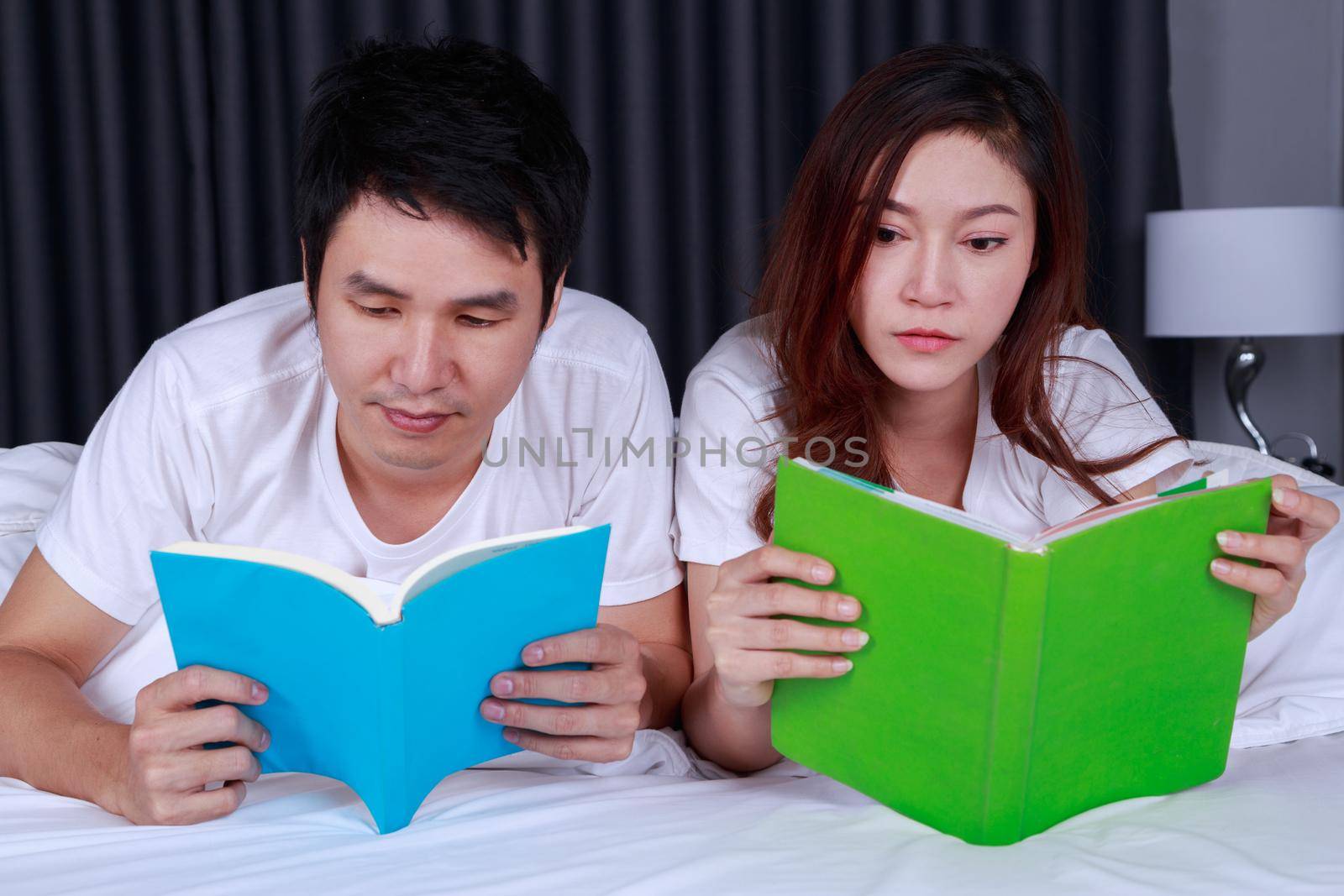 young couple reading a book on bed in bedroom by geargodz