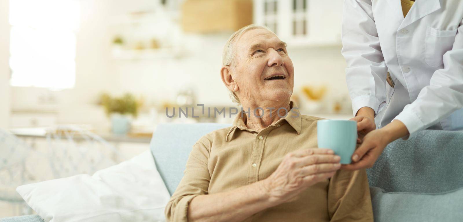 Female doctor in white coat serving a cup to senior citizen at his living room while helping him