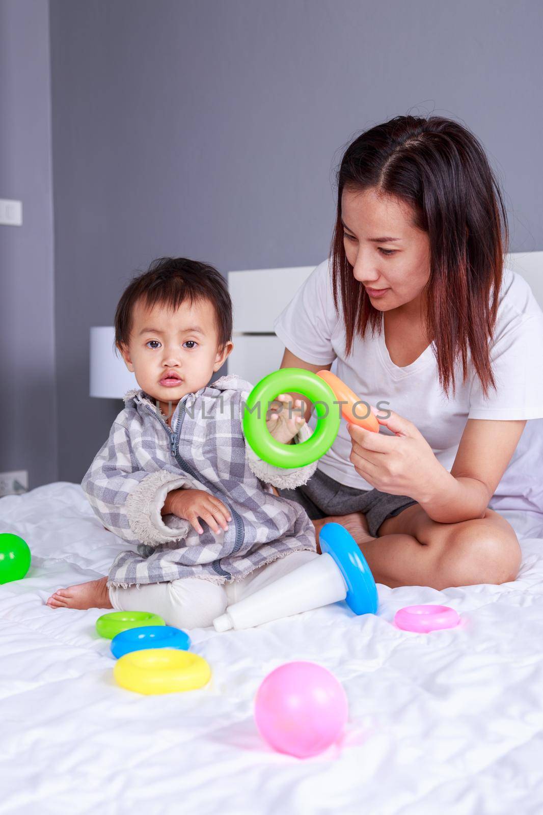 baby playing toys with mother on bed  by geargodz