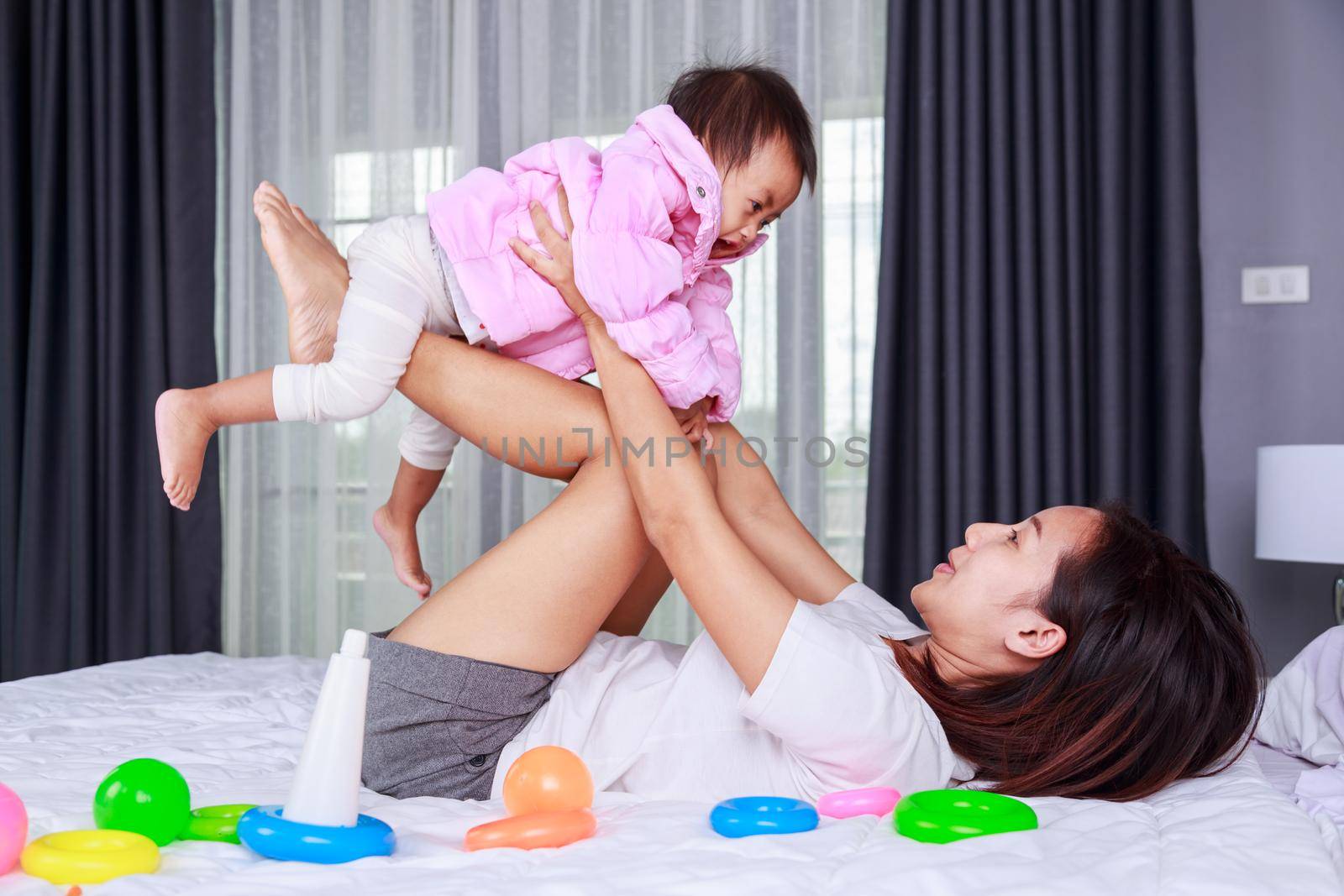 mother playing with her baby on a bed in the bedroom