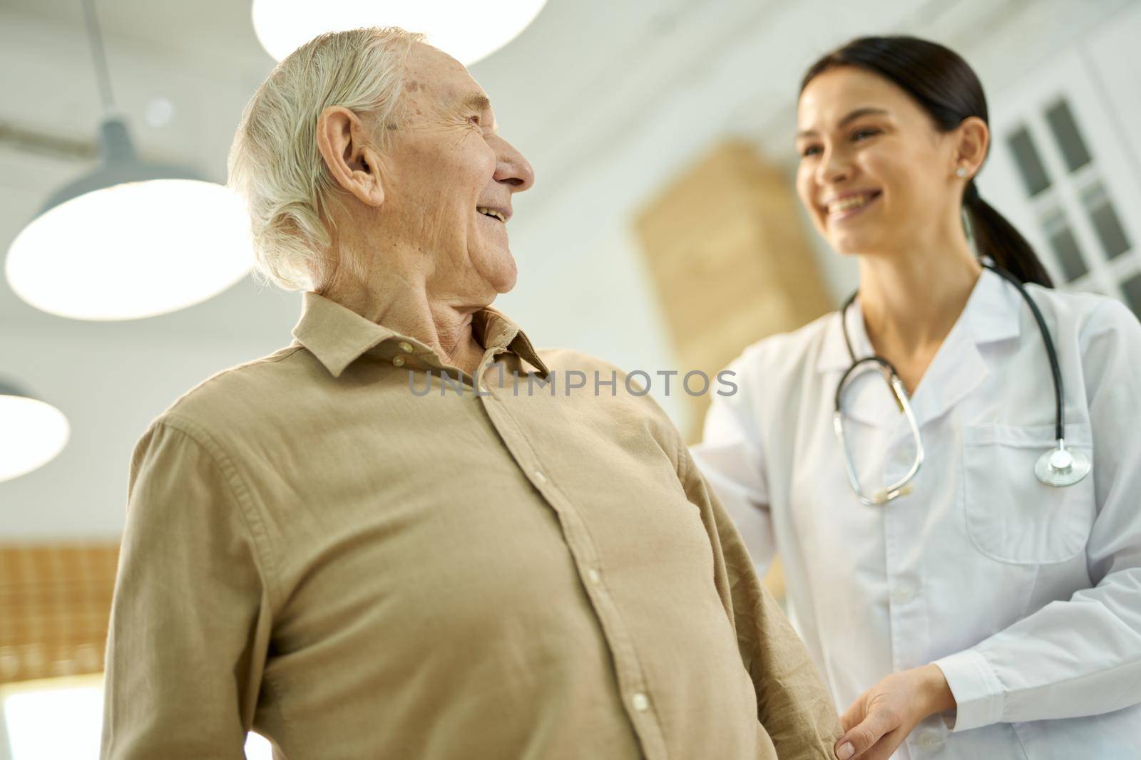 Cheerful aged man looking at his family doctor by friendsstock