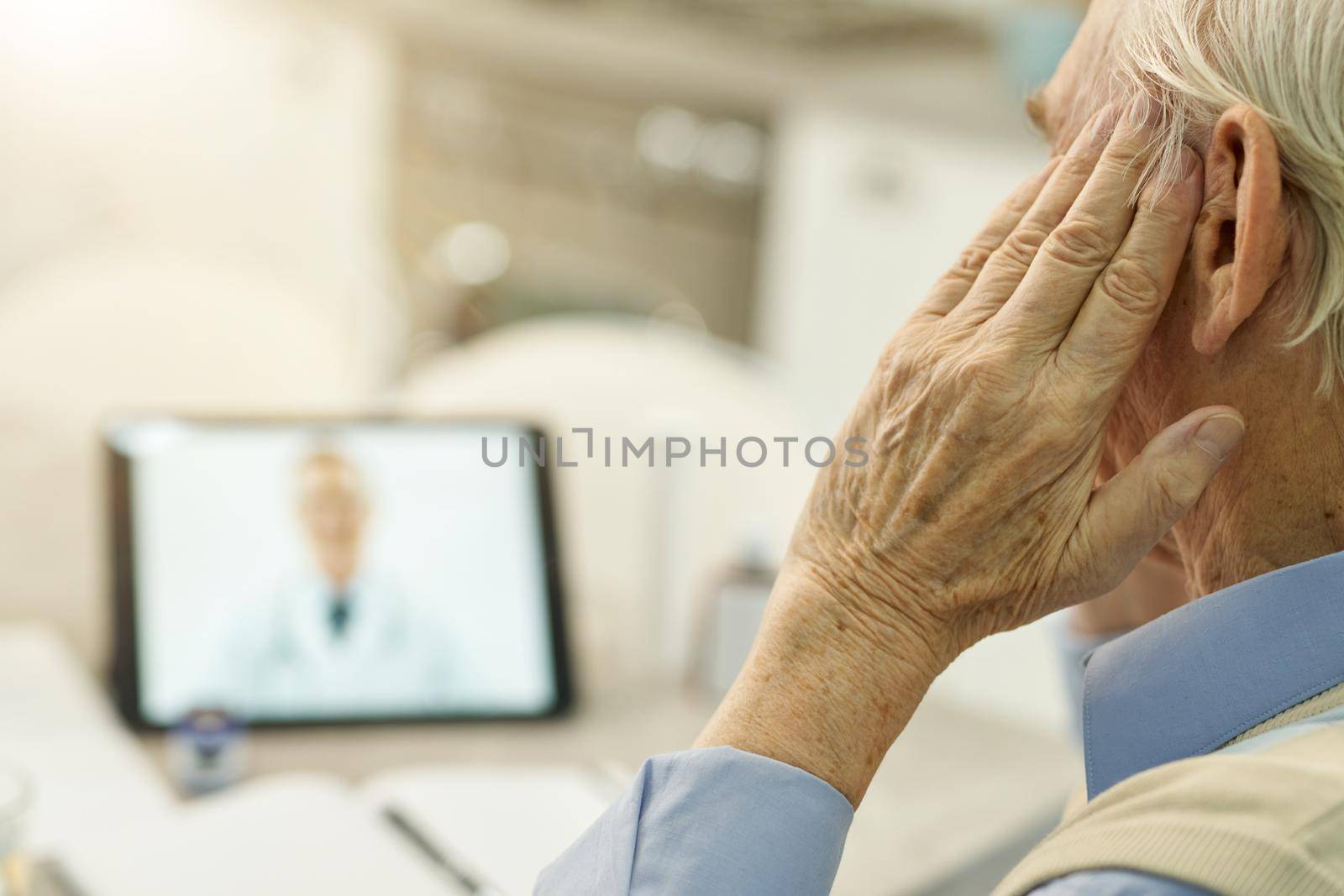 Fragment photo of elderly man touching his head while having a video online consultation with medical specialsit