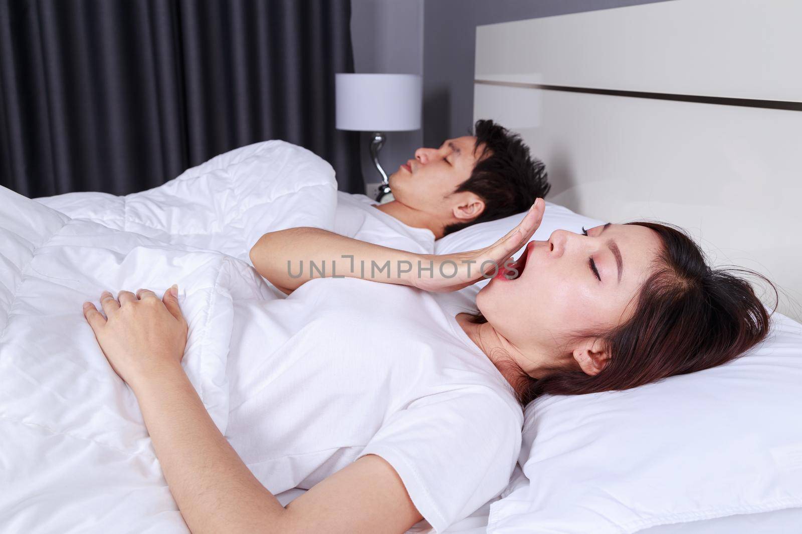 woman yawning and her husband sleeping on bed by geargodz