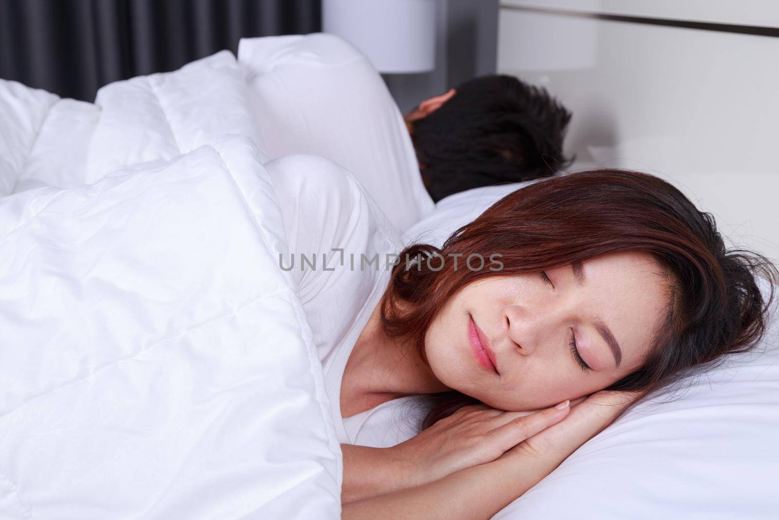 young woman sleeping with her husband in a comfortable bed at home