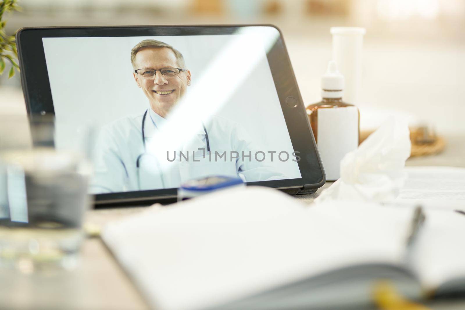 Copy space photo of tablet secured on the table and set to a video-call with family doctor