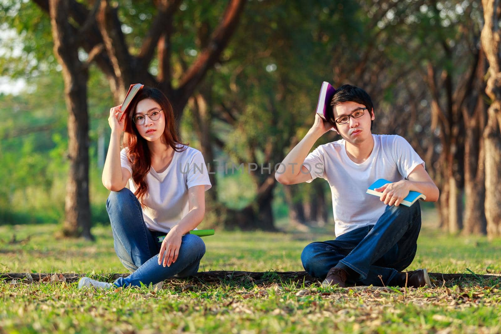 man and woman sitting and reading a book in the park